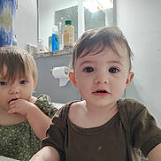 Evy joined the competition — help win amazing prizes! toddler, child, baby, face, expression, indoor, bathroom, mirror, toilet_paper, shower_curtain, curious, chewing, clothing, person, portrait, young_child, hair, skin, eyes, casual