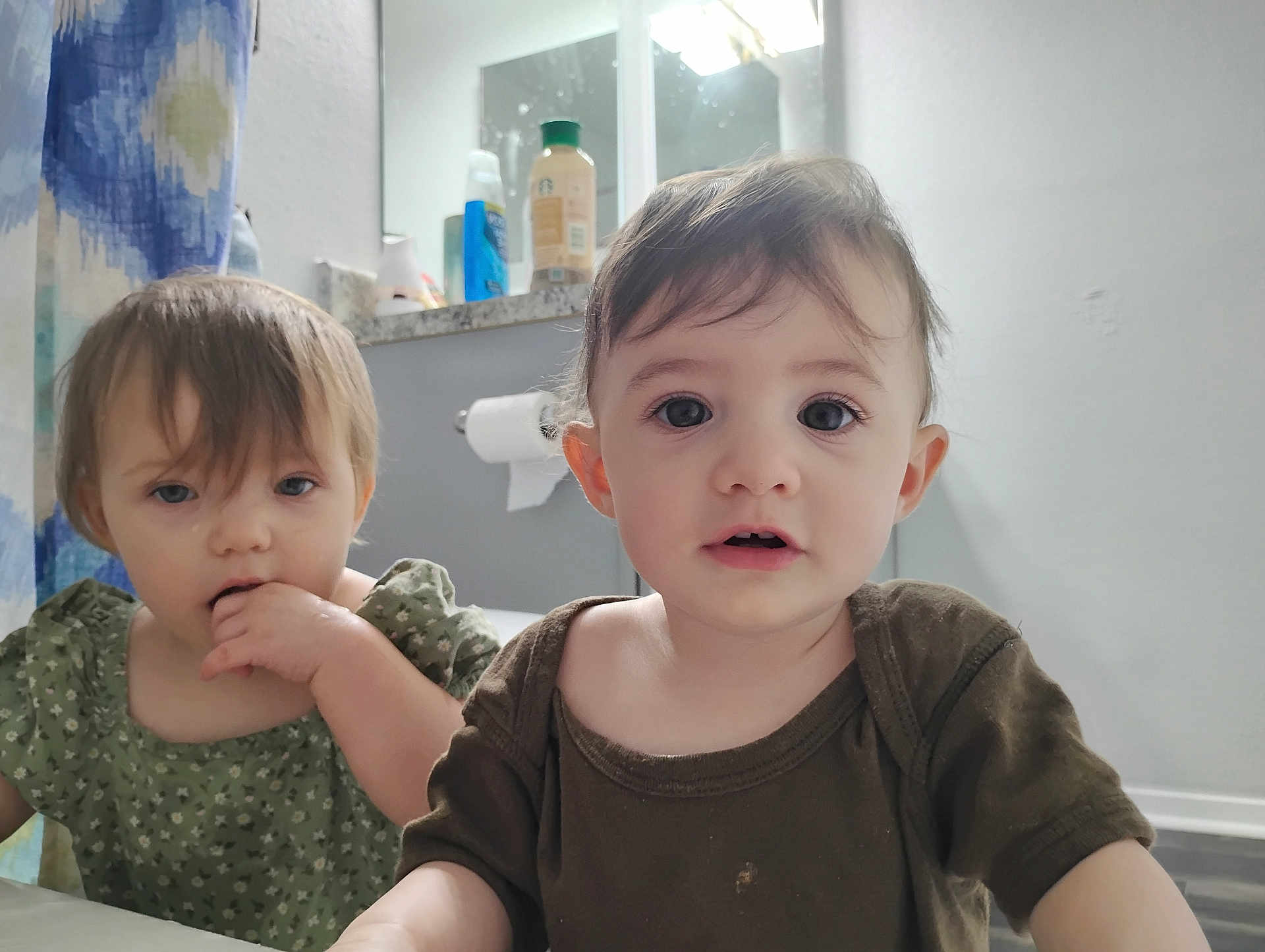 Evy joined the competition — help win amazing prizes! toddler, child, baby, face, expression, indoor, bathroom, mirror, toilet_paper, shower_curtain, curious, chewing, clothing, person, portrait, young_child, hair, skin, eyes, casual