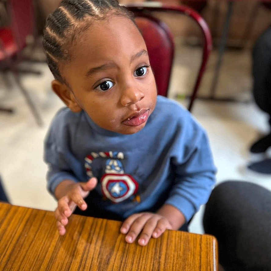 Chris Junior a rejoint le concours — aidez-le/la à gagner de superbes lots ! bodypart, child, diningtable, face, female, finger, furniture, girl, hand, hardwood, head, indoors, interiordesign, person, photography, plywood, portrait, restaurant, table, wood