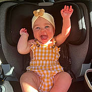 Wrenleigh joined the competition — help win amazing prizes! baby, car_seat, child, smiling, happy, headband, yellow_clothing, checkered_pattern, arms_up, barefoot, car_interior, sunlight, seatbelt, infant, cute, joy, portrait, sitting, closeup, person