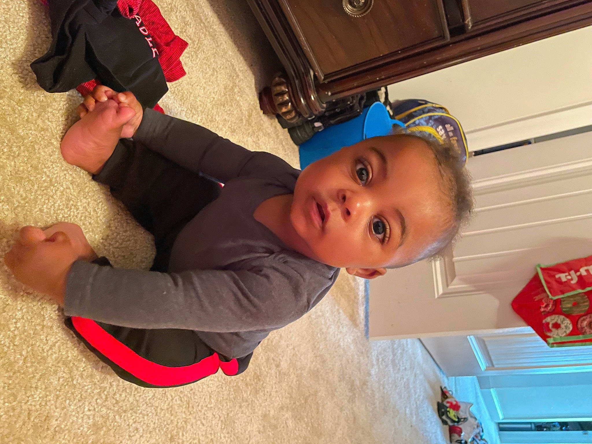 Kyler is registered to the contest to win money with this photo: baby, baby_toddler_clothing, child, flooring, fun, happy, hat, leisure, people, person, play, product, red, room, smile, sock, standing, t_shirt, toddler, vacation