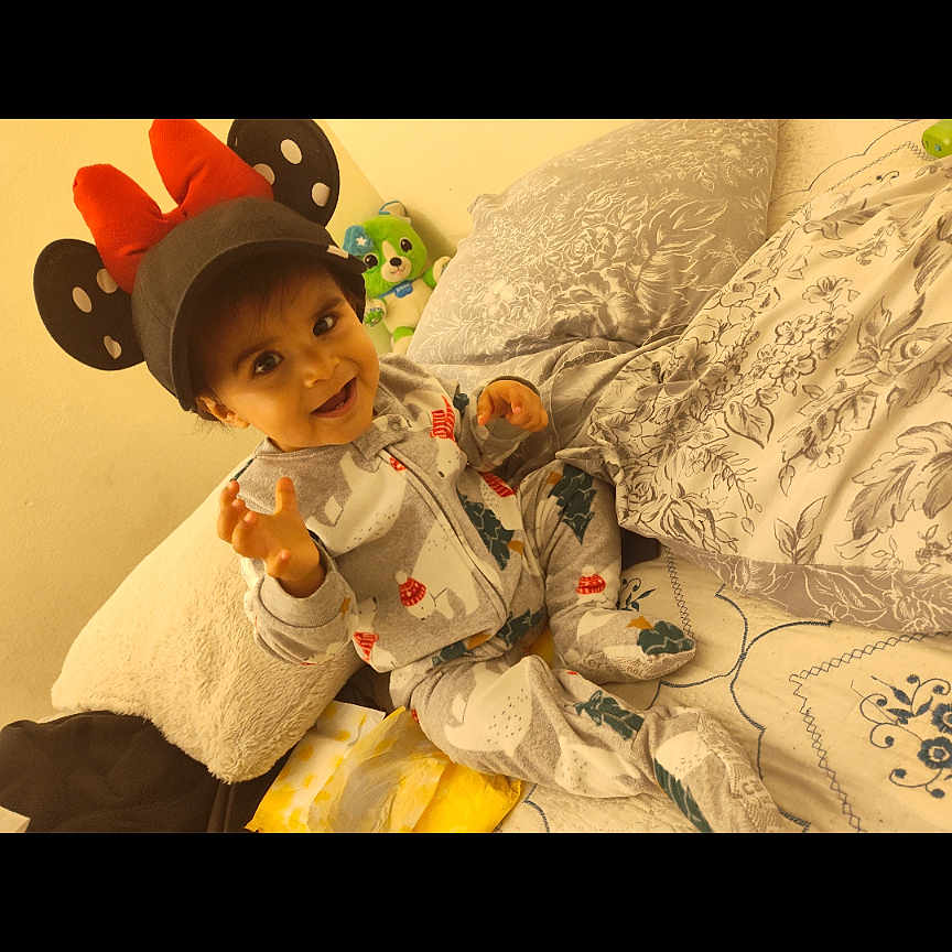 Devin joined the competition — help win amazing prizes! toddler, child, hat, minnie_mouse, ears, red_bow, smiling, bed, pillow, plush_toy, patterned_bedspread, indoor, cute, cozy, happy, person, clothing, baby, portrait, young_child