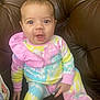 baby, child, infant, tie_dye, colorful_clothing, sitting, couch, leather, brown, cute, wide_eyes, expression, indoors, portrait, person, happy, small_hands, comfortable, young, cozy