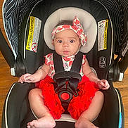 Renesme joined the competition — help win amazing prizes! baby, car_seat, infant, headband, red_clothing, straps, wooden_floor, wide_eyes, sitting, child, safety_harness, expression, indoors, cute, person, head_support, foot, hand, fabric, warning_label