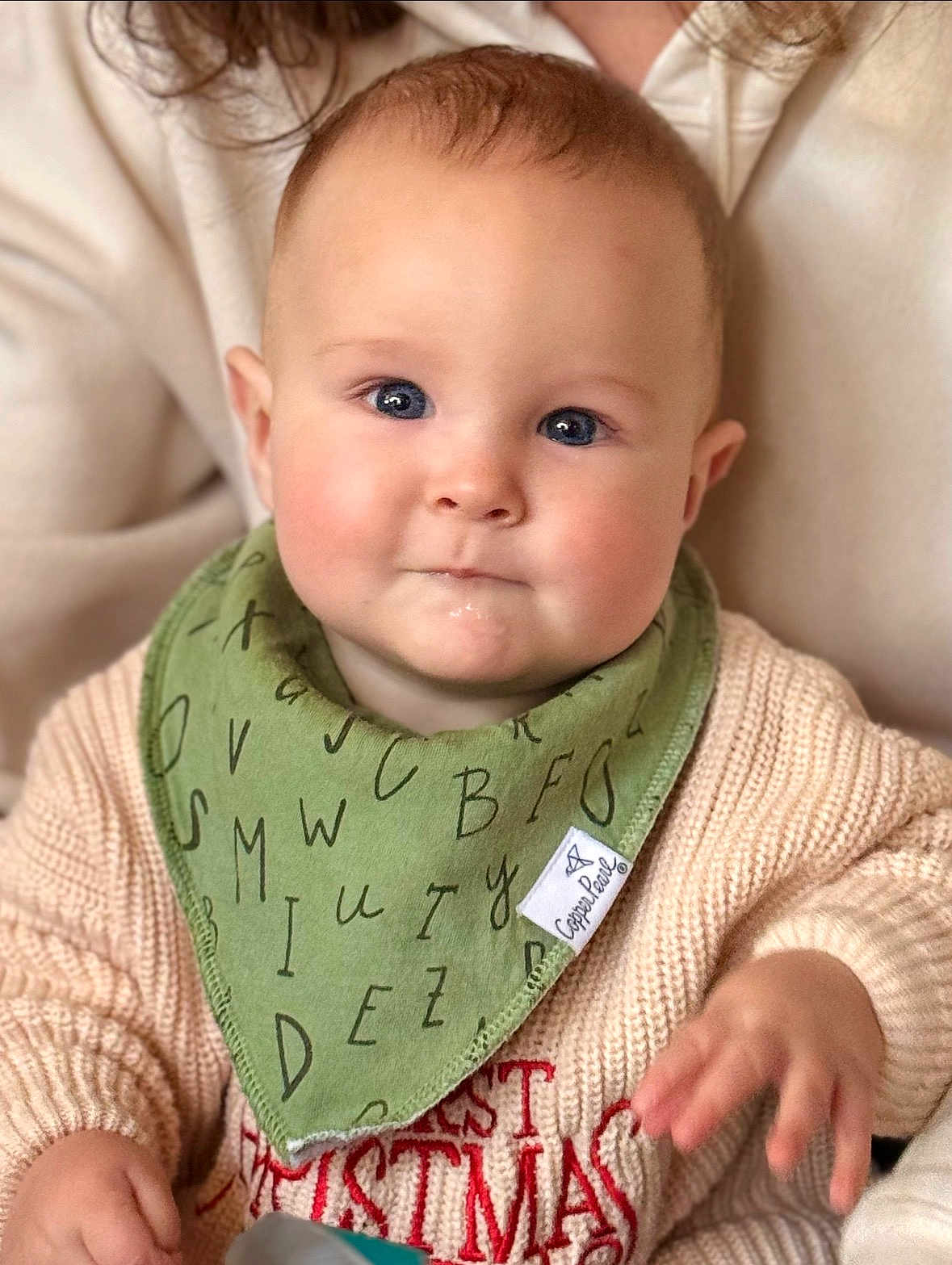 Asher joined the competition — help win amazing prizes! baby, infant, child, bib, bandana_bib, sweater, christmas_sweater, blue_eyes, chubby_cheeks, hand, close_up, portrait, indoor, caregiver, knitwear, soft_lighting, drool, neutral_expression, cozy, blurred_background