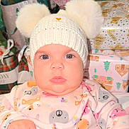 Sarahis is registered to the contest to win money with this photo: baby, child, face, hat, knit_hat, pom_poms, onesie, animal_print, gift_wrap, presents, holiday, indoors, cute, chubby_cheeks, portrait, person, infant, closeup, festive, soft_lighting