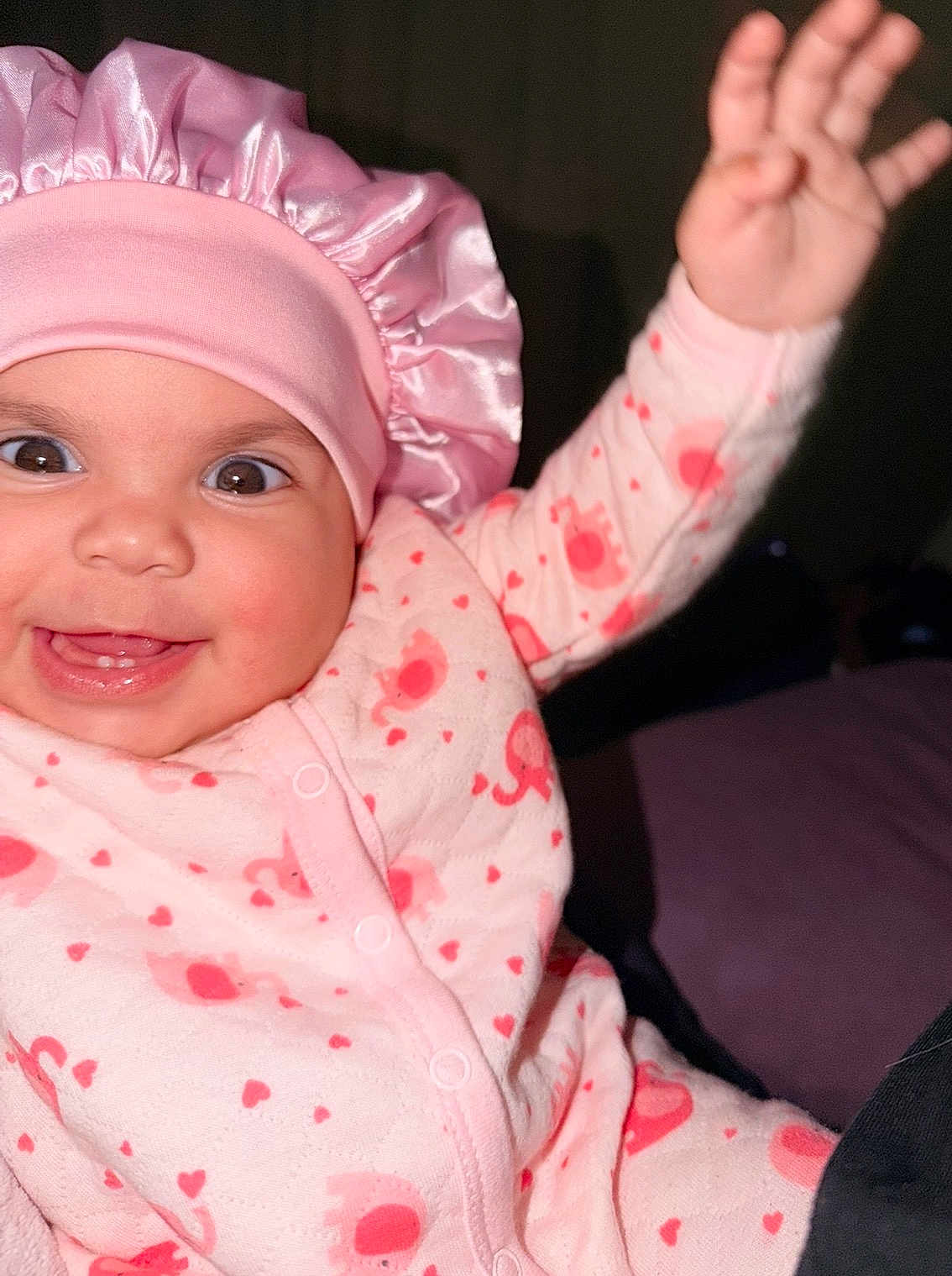 Sarahis is registered to the contest to win money with this photo: baby, child, pink_bonnet, pink_onesie, elephant_pattern, hearts, smiling, happy, waving_hand, cute, infant, face, headwear, clothing, portrait, indoors, closeup, cheerful, small_teeth, joy