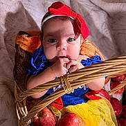 Sarahis is registered to the contest to win money with this photo: baby, infant, child, basket, apples, red_bow, blue_dress, yellow_skirt, hand, face, headband, fruit, cute, indoors, soft_blanket, plush, portrait, closeup, person, costume