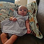 baby, child, dress, couch, pillow, pattern, horse, indoor, window, curtains, person, skin, head, legs, arm, furniture, comfort, resting, casual, portrait