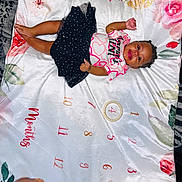 Emonnie is registered to the contest to win money with this photo: baby, blanket, child, clothing, cute, face, floral_pattern, hand, happy, head, indoor, infant, lying_down, months_marker, person, portrait, shirt, skin, skirt, smiling