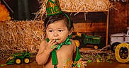 Zealand joined the competition — help win amazing prizes! baby, birthday, birthday_cake, cake, celebration, child, costume, farmer_theme, festive, food, green, hay_bales, indoor, party_hat, portrait, sitting, smiling, toddler, toy_tractors, wooden_floor