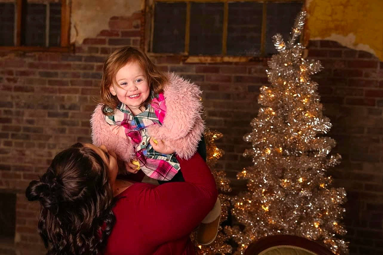 Aubree is registered to the contest to win money with this photo: blond, brown_hair, christmas, christmas_ornament, christmas_tree, event, flash_photography, fun, hairstyle, happy, holiday, holiday_ornament, joy, leisure, magenta, ornament, person, sitting, smile, toddler