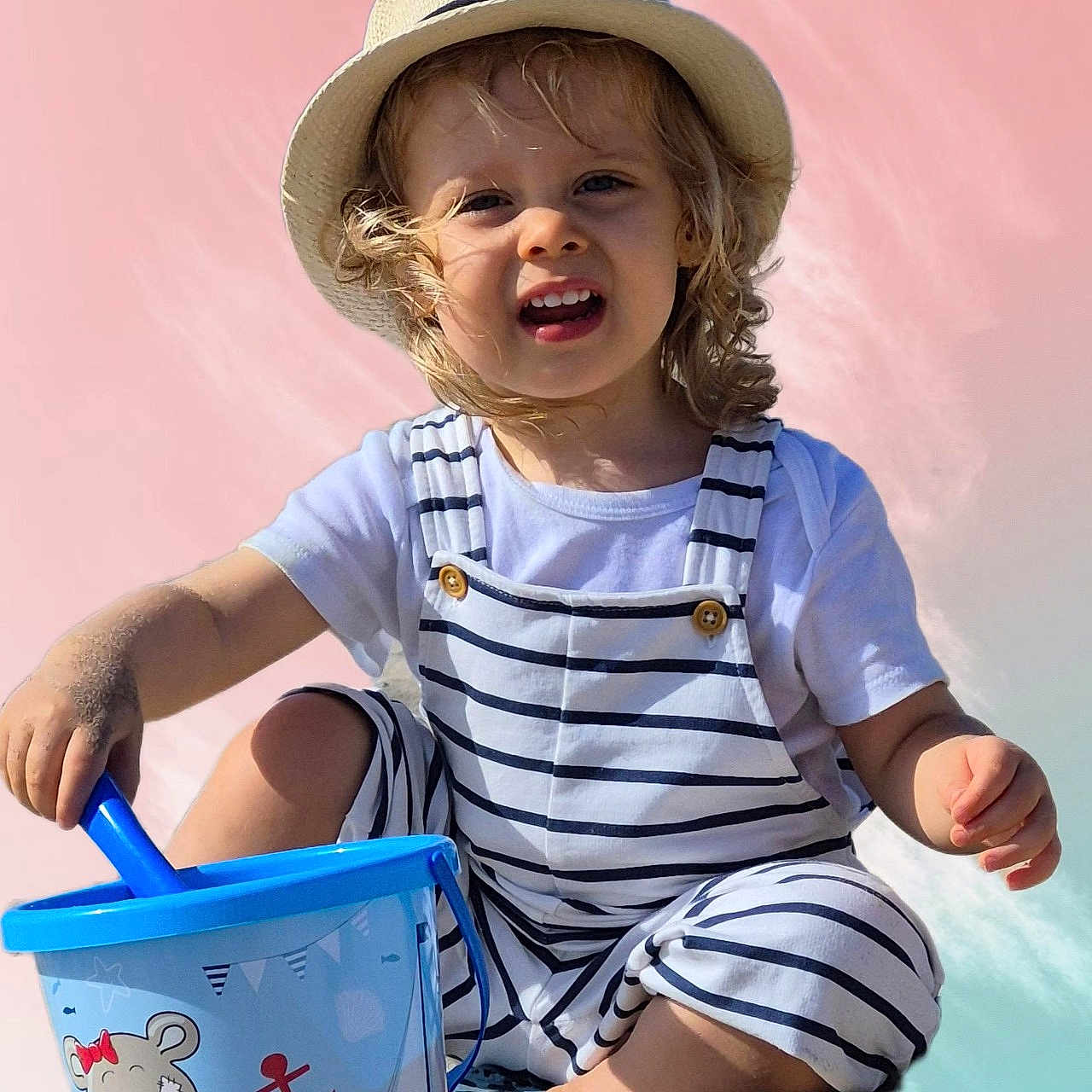 Maël a rejoint le concours — aidez-le/la à gagner de superbes lots ! blue, bucket, child, curly_hair, cute, fun, happy, hat, nautical, outdoor, person, playing, portrait, sand, smiling, striped_clothing, summer, toddler, toy, white