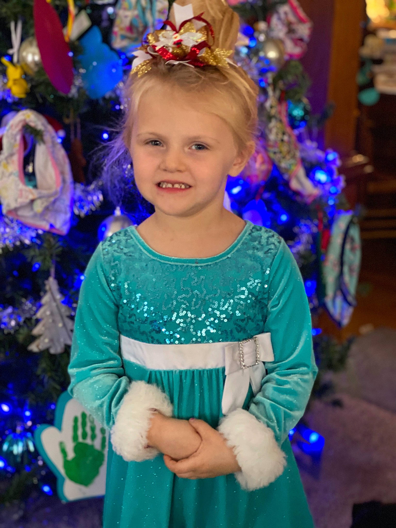 Ella is registered to the contest to win money with this photo: beauty, blue, christmas_decoration, christmas_ornament, christmas_tree, electric_blue, event, fashion, fashion_design, fun, happy, holiday, holiday_ornament, joy, person, purple, sleeve, smile, standing, toddler
