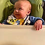 baby, high_chair, bib, food, smile, child, infant, hand, face, clothing, seat, green, blue, cute, young, indoor, feeding, expression, person, toddler
