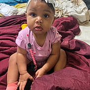 Zaya joined the competition — help win amazing prizes! baby, bed, blanket, bow, child, curious, cute, expression, face, girl, hands, headband, indoor, infant, person, pink_clothing, seated, skin, sock, toddler