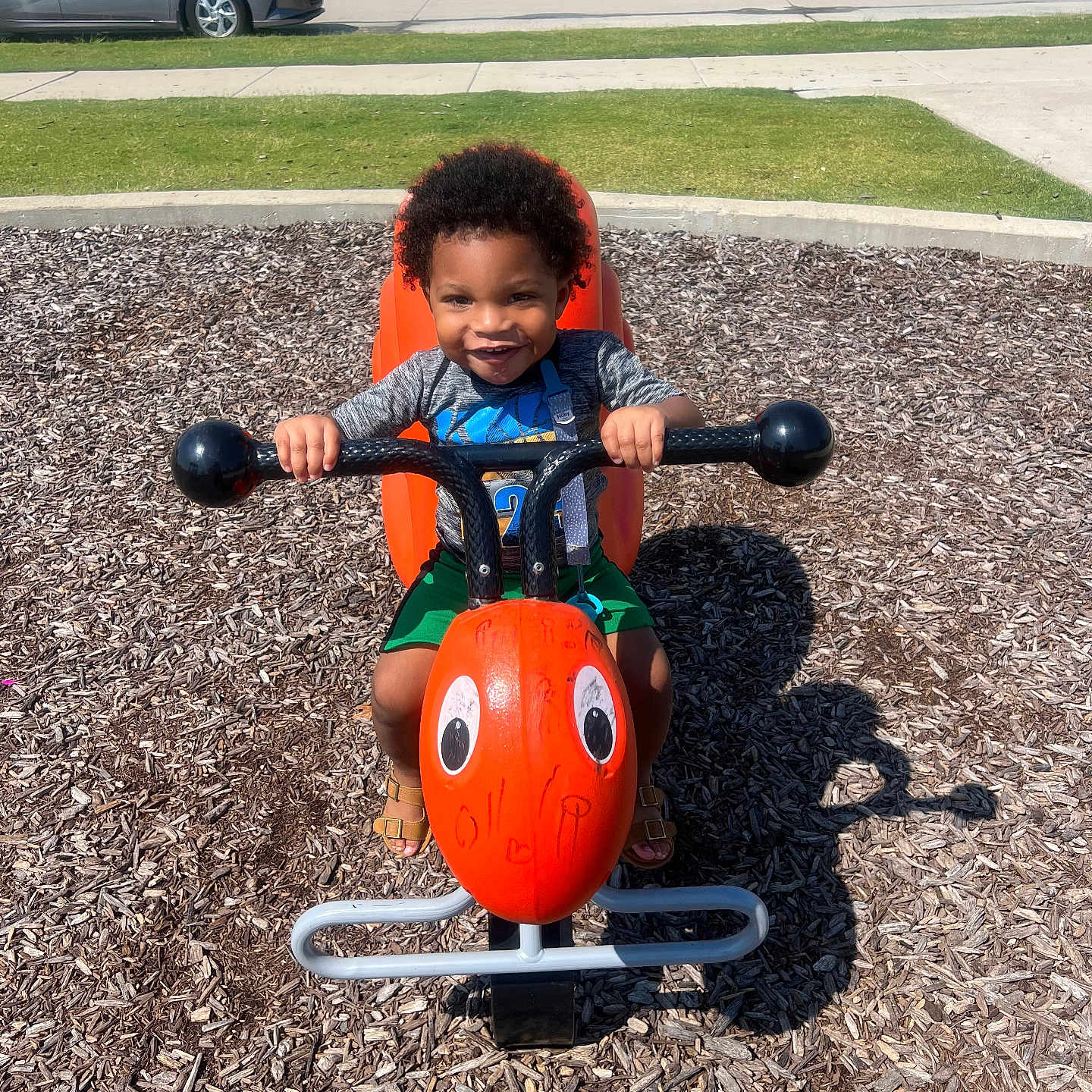 Zion joined the competition — help win amazing prizes! car, child, clothing, face, fun, grass, happy, orange, outdoor, play, playground, sidewalk, smiling, spring_rider, suburban, summer, sunny, toddler, toy, wood_chips