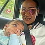 baby, woman, car, seatbelt, sunglasses, no_smoking_sign, window, child, person, hand, face, clothing, reflection, interior, seat, nature, greenery, casual, portrait, family