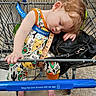Charlie is registered to the contest to win money with this photo: child, toddler, sleeping, shopping_cart, walmart, colorful_clothing, taco_print, barefoot, purse, outdoor, concrete_floor, metal_cart, clothing, head, hand, footwear, person, retail, casual, resting