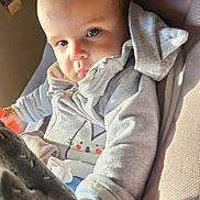 Nino participe au concours pour gagner de l'argent avec cette photo : baby, bodypart, clothing, coat, couch, face, finger, furniture, hand, head, hood, hoodie, jacket, knitwear, pants, person, photography, portrait, sweater, sweatshirt