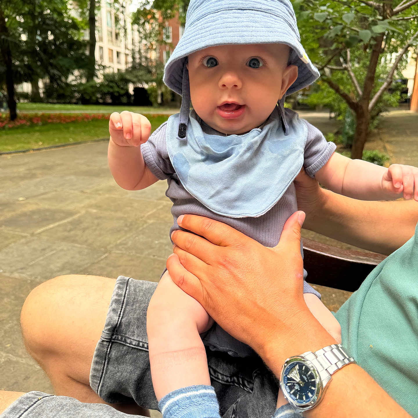 Oleksandr joined the competition — help win amazing prizes! adult, baby, bench, bib, buildings, casual, child, clothing, face, greenery, hand, hat, legs, outdoor, person, portrait, socks, summer, trees, watch