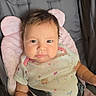 baby, infant, child, stroller, harness, seated, portrait, face, eyes, hair, cheeks, serious_expression, indoors, pink_cushion, baby_clothing, onesie, safety_straps, photography, close_up, full_body