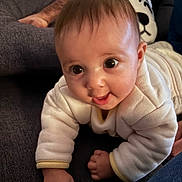 Lilith a rejoint le concours — aidez-le/la à gagner de superbes lots ! baby, infant, tummy_time, couch, sofa, onesie, white_clothing, wide_eyes, smile, close_up, portrait, indoor, hand, arm, pillow, plush_toy, panda_pillow, adult_arm, skin, cute