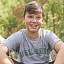 boy, casual_clothing, child, daylight, face, greenery, happy, leisure, nature, outdoor, person, portrait, relaxed, short_hair, sitting, smiling, sunlight, teenager, tshirt, young