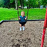 Aiden is registered to the contest to win money with this photo: toddler, child, swing, playground, park, grass, trees, greenery, happy, smiling, outdoor, daytime, casual_clothing, blue_shirt, sneakers, play, recreation, fun, nature, metal_chains