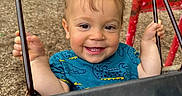 Aiden joined the competition — help win amazing prizes! toddler, child, smiling, swing, playground, grass, wood_chips, blue_shirt, crocodile_pattern, happy, outdoor, person, face, holding, metal_chain, red_playground_equipment, park, daylight, young_child, fun