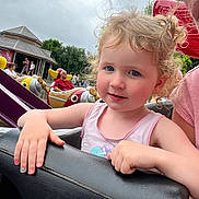 Julia a rejoint le concours — aidez-le/la à gagner de superbes lots ! amusement_park, background, child, cloudy_sky, colorful, curly_hair, daytime, entertainment, face, family, fun, hand, nail_polish, outdoor, park, people, pink_tank_top, ride, smile, toddler