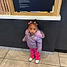 Gianna is registered to the contest to win money with this photo: child, girl, standing, purple_jacket, pink_pants, white_shoes, bows, hair, indoor, tile_floor, wall, wood_frame, sign, text, curious, portrait, person, clothing, casual, young