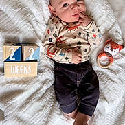 Jasper joined the competition — help win amazing prizes! baby, infant, child, blanket, wooden_blocks, toy, knitted_toy, fox_pattern, clothing, cute, lying_down, indoor, playful, hand_on_face, expression, soft_texture, warm, portrait, young, smiling
