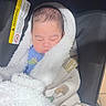 baby, blanket, blue_shirt, bundled, car_seat, closed_eyes, clothing, cozy, face, fluffy_blanket, indoors, infant, newborn, peaceful, photograph, portrait, safety_label, seated, sleeping, vehicle