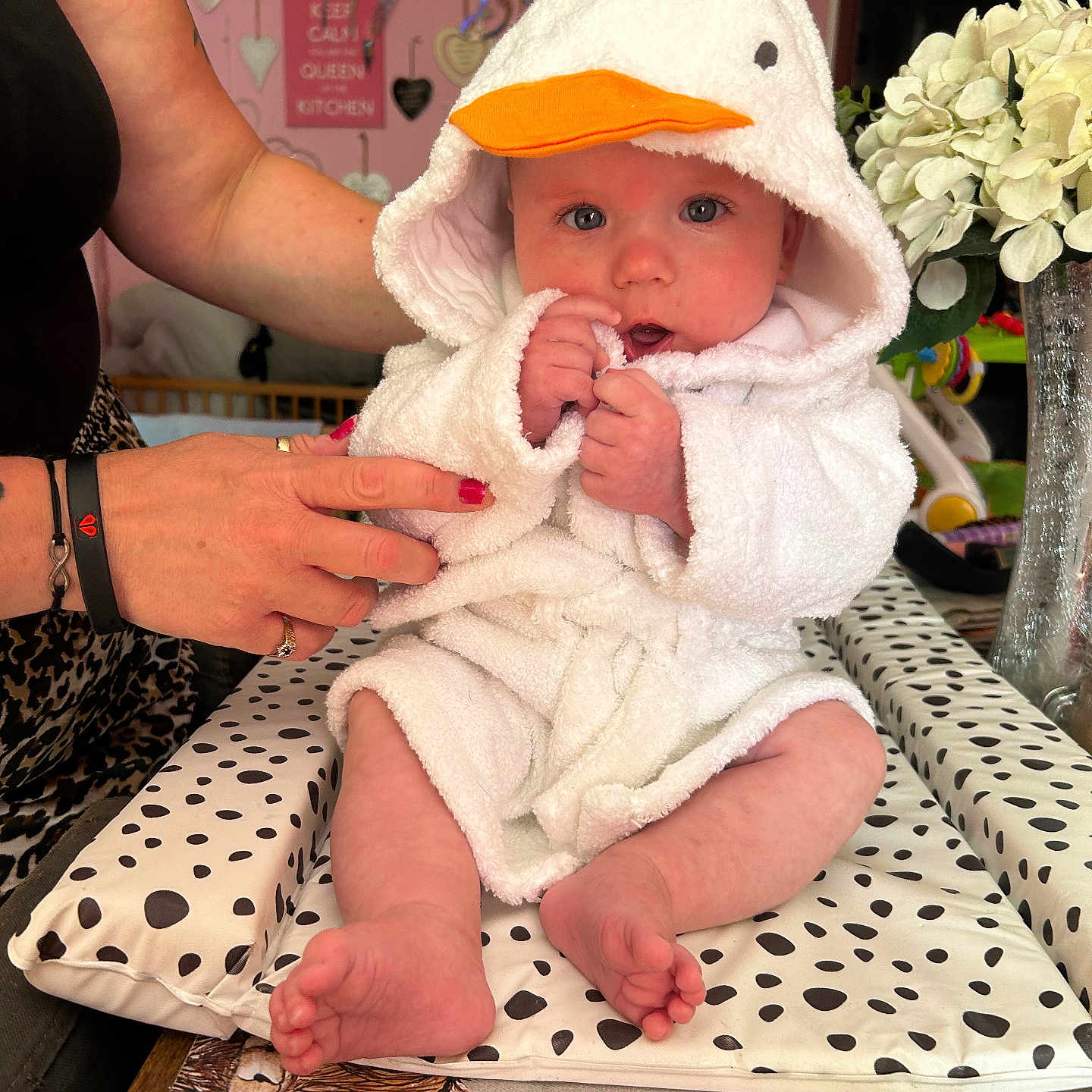 Sonny joined the competition — help win amazing prizes! adult_hand, baby, child, cushion, decor, duck_hood, flowers, hands, heart_decorations, indoor, nail_polish, orange_beak, person, pink_wall, polka_dots, portrait, sitting, table, vase, white_robe