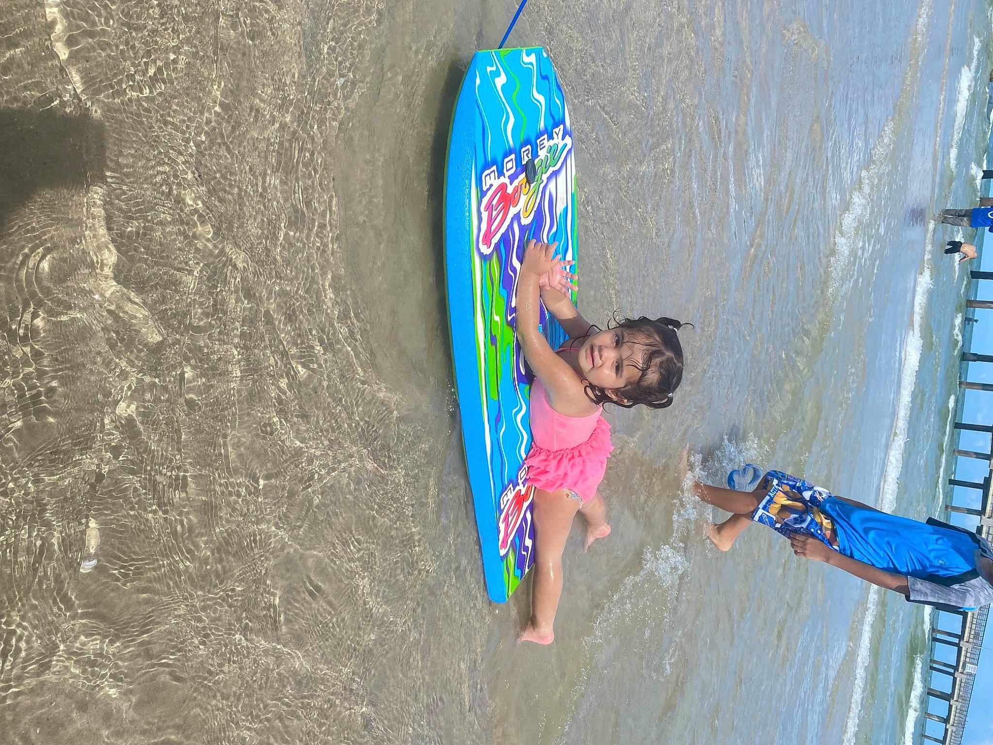 Alita is registered to the contest to win money with this photo: azure, beach, blue, boats_and_boating_equipment_and_supplies, child, fun, happy, leisure, outdoor_recreation, paint, person, play, recreation, sand, shorts, sports, surface_water_sports, surfing_equipment, water, wave