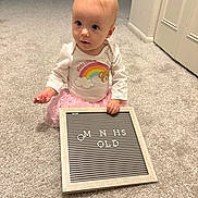 Adalyn is registered to the contest to win money with this photo: baby, child, infant, carpet, letter_board, pink_tutu, white_shirt, rainbow, bear_graphic, indoor, person, cute, holding, sitting, curious, soft_lighting, floor, room, toy, letters
