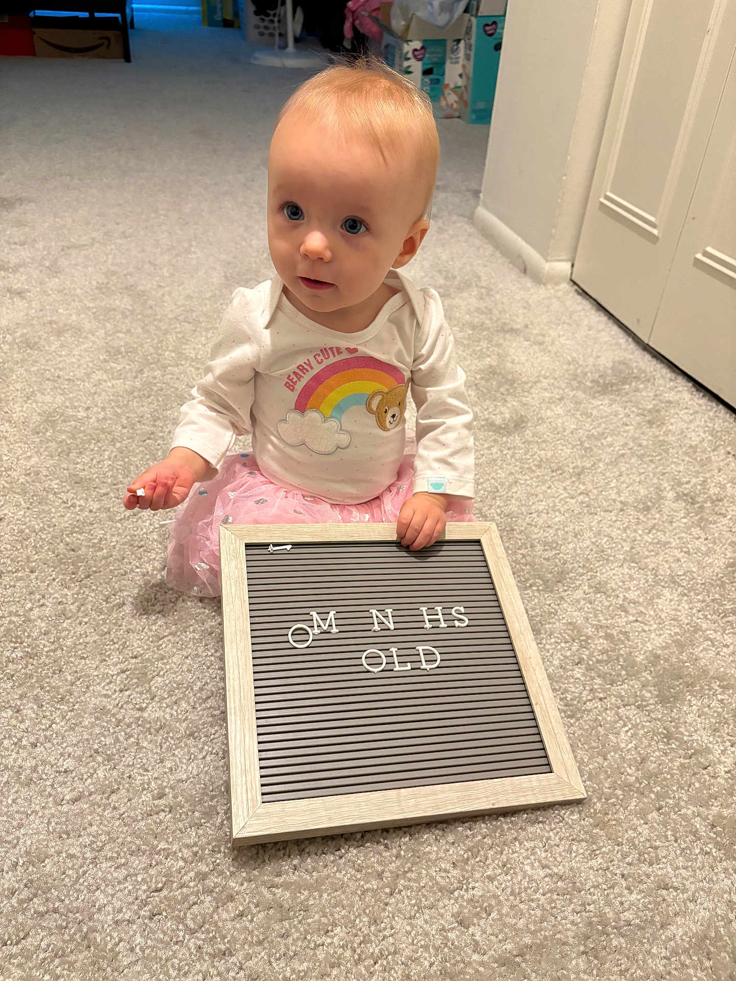 Adalyn is registered to the contest to win money with this photo: baby, child, infant, carpet, letter_board, pink_tutu, white_shirt, rainbow, bear_graphic, indoor, person, cute, holding, sitting, curious, soft_lighting, floor, room, toy, letters