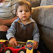 Atlas is registered to the contest to win money with this photo: child, toddler, boy, portrait, sitting, indoors, couch, adult, toy_car, remote_control_car, stitch, disney, toy_box, playtime, brown_hair, blue_eyes, serious_expression, family, living_room, photography