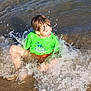 beach, casual_clothing, child, fun, green_shirt, happy, nature, outdoor, person, playing, sand, sitting, splash, splashing, summer, sunlight, water, water_droplets, waves, wet_hair