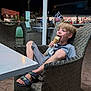 boy, chair, child, cone, happy, ice_cream, market, night, outdoor, pavement, people, relaxed, sandals, shop, shorts, smiling, streetlight, table, tshirt, wicker