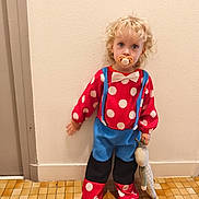 Mya participe au concours pour gagner de l'argent avec cette photo : barefoot, blue_clothing, bow_tie, child, costume, curly_hair, cute, indoor, pacifier, person, polka_dot, portrait, red_clothing, standing, suspenders, tile_floor, toddler, toy, wall, white_polka_dots