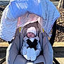 newborn, baby, car_seat, infant, blanket, hat, outdoor, parking_lot, sunlight, clothing, baby_gear, safety_harness, cotton, sleeping, cute, soft_texture, gray, white, peaceful, newborn_clothing
