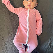 Terrie is registered to the contest to win money with this photo: baby, baby_garment, bedspread, child, curious_expression, cute, gray_background, indoors, infant, infant_fashion, lying_down, onesie, person, pink_clothing, portrait, sleepwear, small_child, soft_fabric, striped_clothing, wide_eyes
