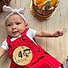 Terrie joined the competition — help win amazing prizes! baby, birthday, cake, candle, celebration, child, cute, dessert, food, fruit_topping, hands, happy, headband, infant, legs, lying_down, milestone_sticker, red_overalls, smiling, wooden_floor