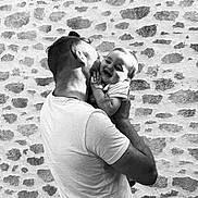 Manoé a rejoint le concours — aidez-le/la à gagner de superbes lots ! man, baby, child, holding, kissing, laughing, black_and_white, stone_wall, affection, joy, outdoor, casual_clothing, short_sleeves, portrait, parent_and_child, emotion, love, smile, family, tenderness