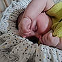 baby, sleeping, infant, blanket, crib, yellow_clothing, hand, face, peaceful, soft_texture, closeup, indoors, cozy, child, toddler, rest, cute, newborn, portrait, nap