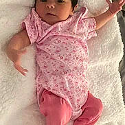 Aria is registered to the contest to win money with this photo: baby, infant, pink_clothing, onesie, blanket, lying_down, stretching, cute, newborn, soft_texture, indoors, child, small_feet, face, head, skin, peaceful, cozy, portrait, relaxing