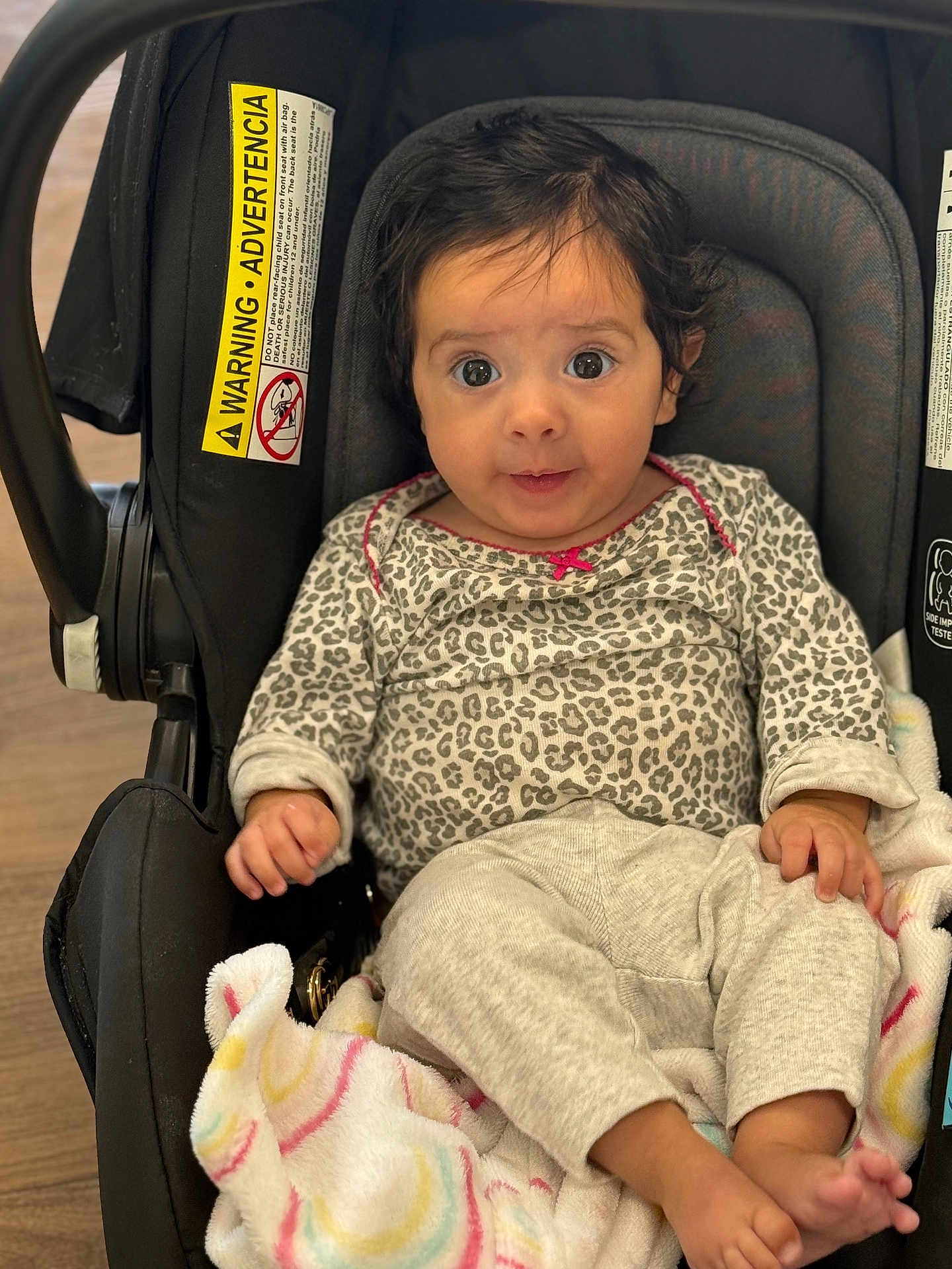 Aria joined the competition — help win amazing prizes! baby, car_seat, blanket, clothing, infant, cute, indoors, person, child, face, smiling, leopard_print, footwear_absent, soft_texture, hand, wooden_floor, sitting, expression, black_frame, cozy