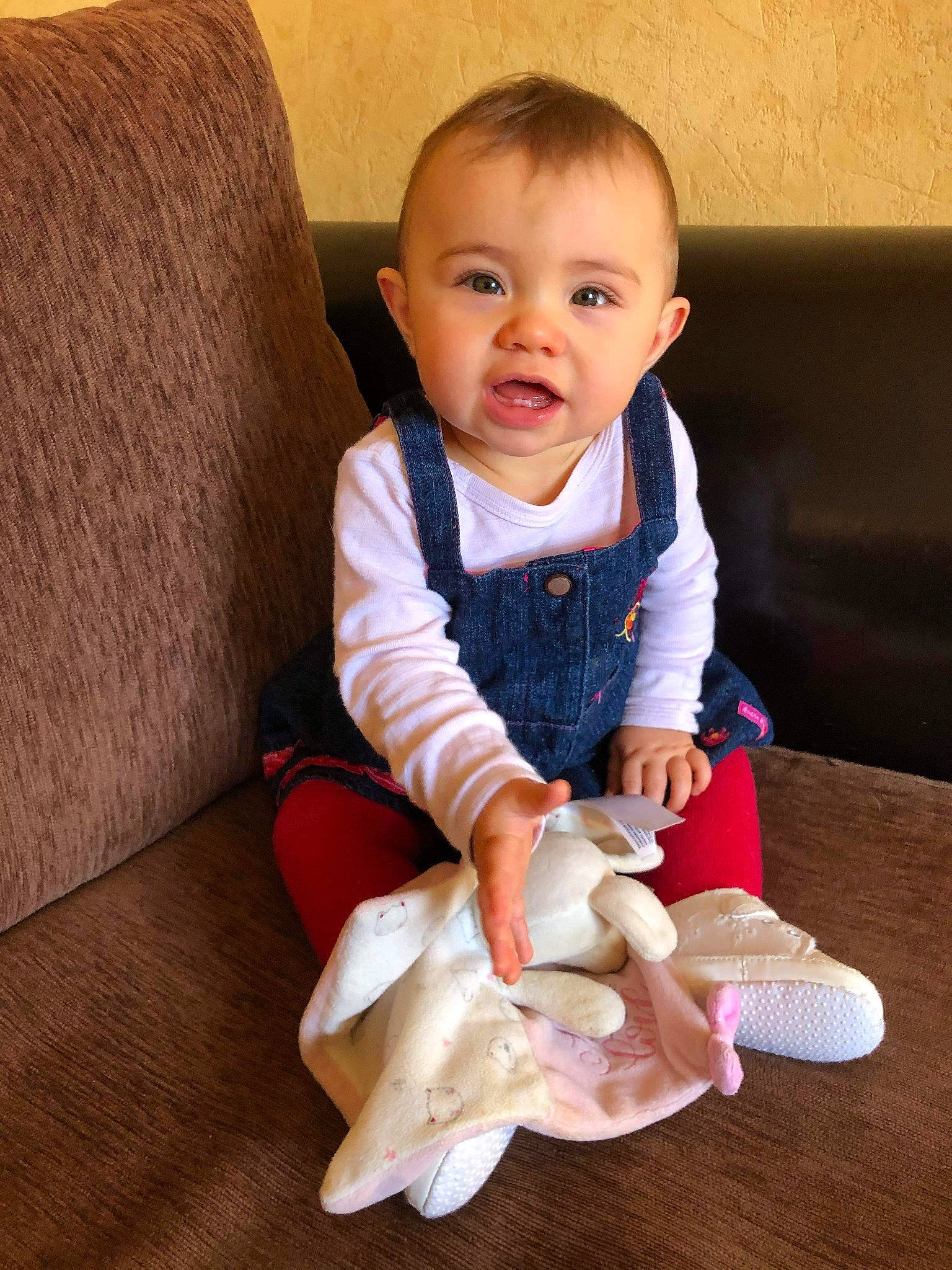 Lou a rejoint le concours — aidez-le/la à gagner de superbes lots ! baby, baby_toddler_clothing, cheek, child, comfort, couch, facial_expression, floor, flooring, foot, human_leg, outerwear, person, sitting, skin, sleeve, smile, sock, thumb, toddler